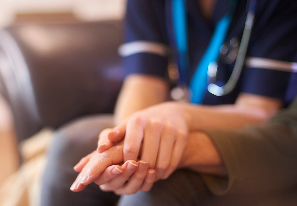 a nurse holding a patients hands