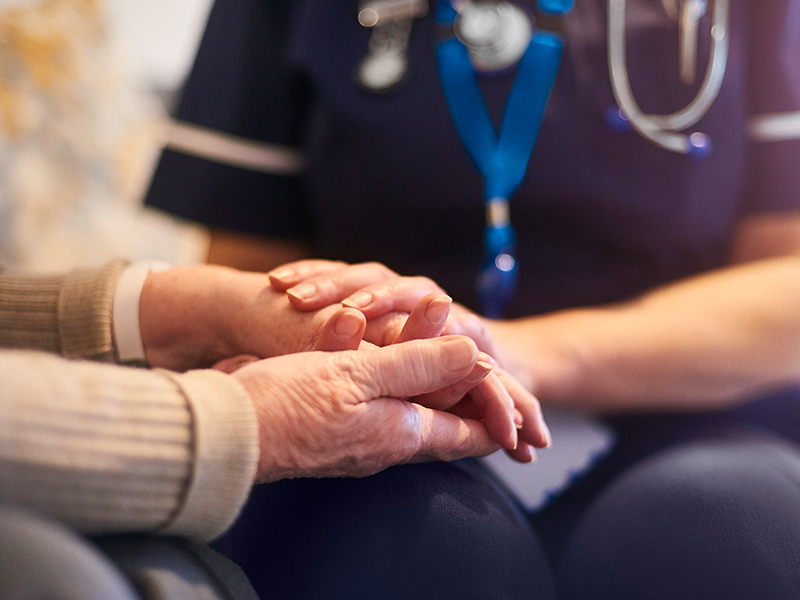 a nurse holding an older persons hands
